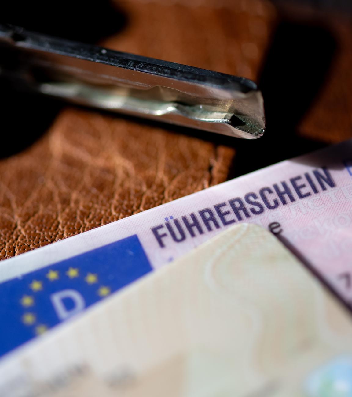 Ein Führerschein, ein Autoschlüssel und ein Personalausweis liegen auf einem Portemonnaie