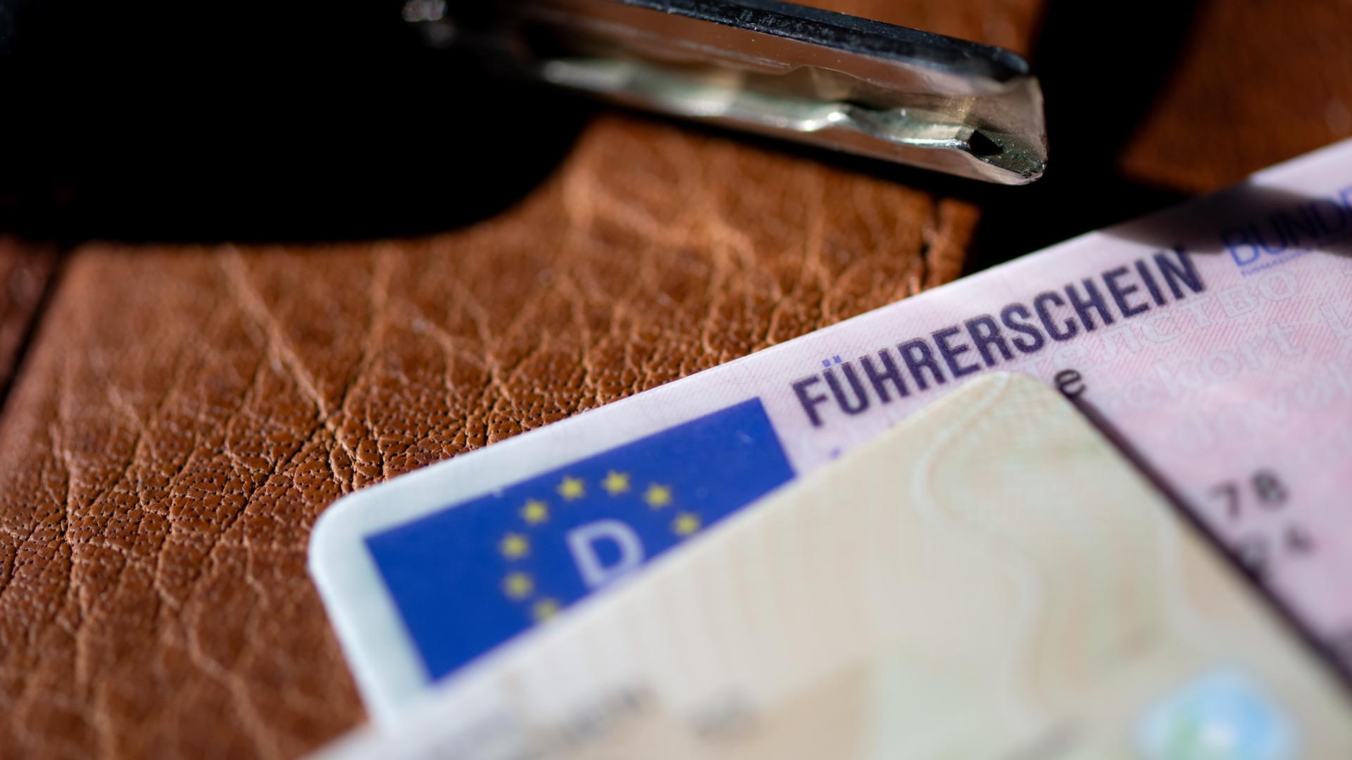 Ein Führerschein, ein Autoschlüssel und ein Personalausweis liegen auf einem Portemonnaie