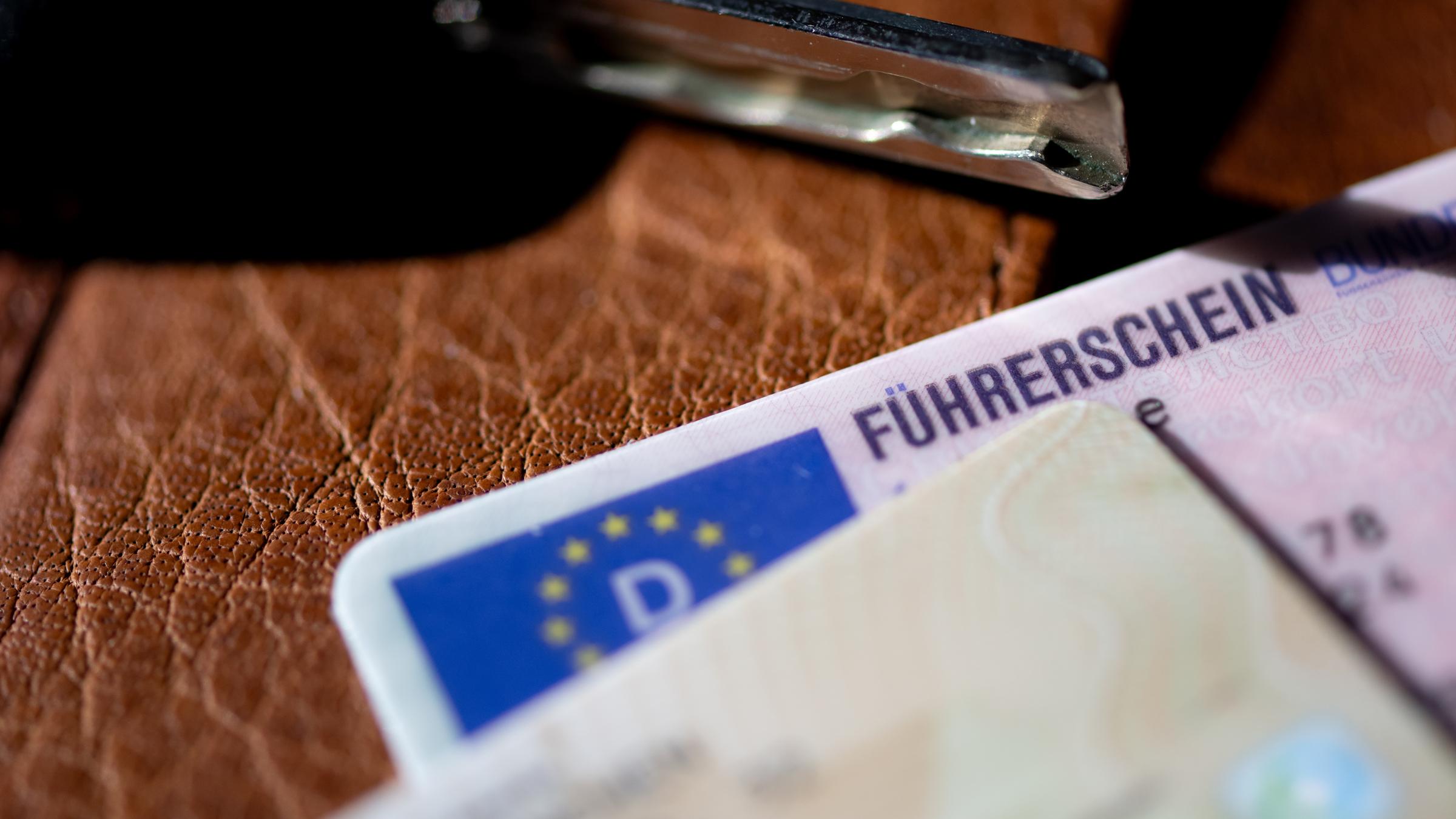 Ein Führerschein, ein Autoschlüssel und ein Personalausweis liegen auf einem Portemonnaie