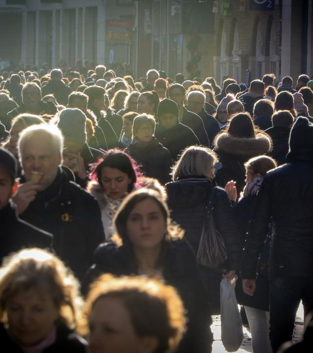 Viele Menschen in der Abendsonne in einer Fußgängerzone.