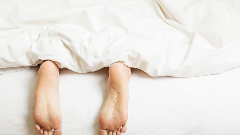 Füße schauen unter Bettdecke hervor