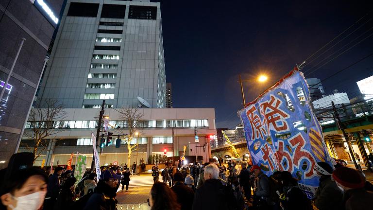 Menschen protestieren vor dem Hauptsitz der Tokyo Electric Power Company mit einem großen Banner gegen Kernkraft.