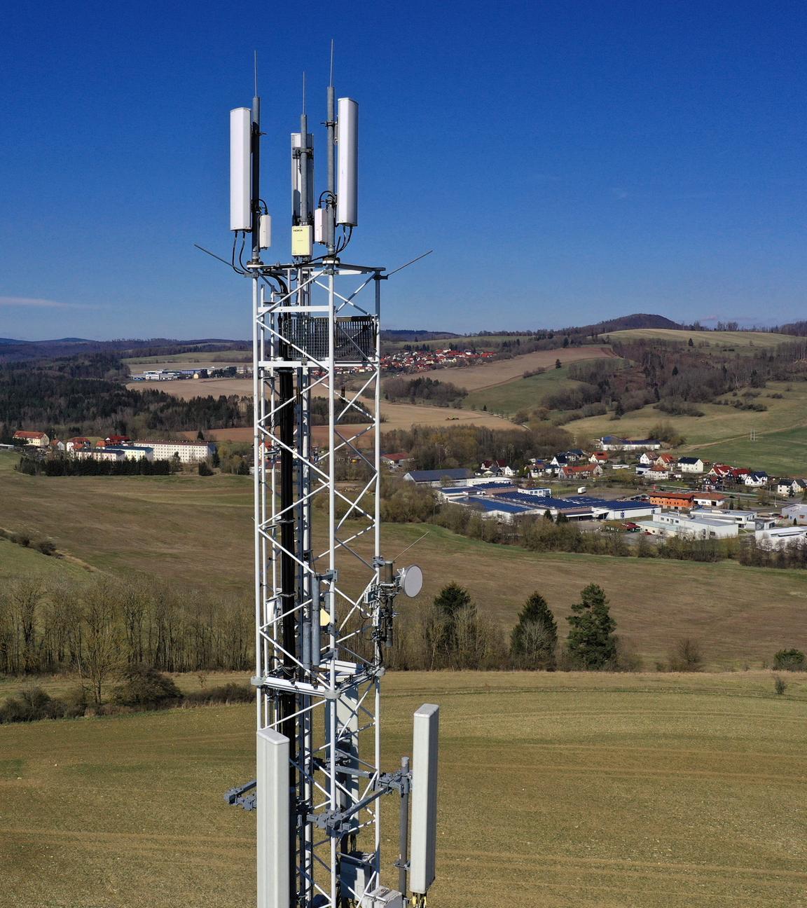 Ein Mobilfunkmast steht in ländlicher Umgebung. 
