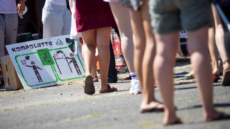 Festivalbesucher warten vor einer "Kompolette", einer so genannten Komposttoilette.