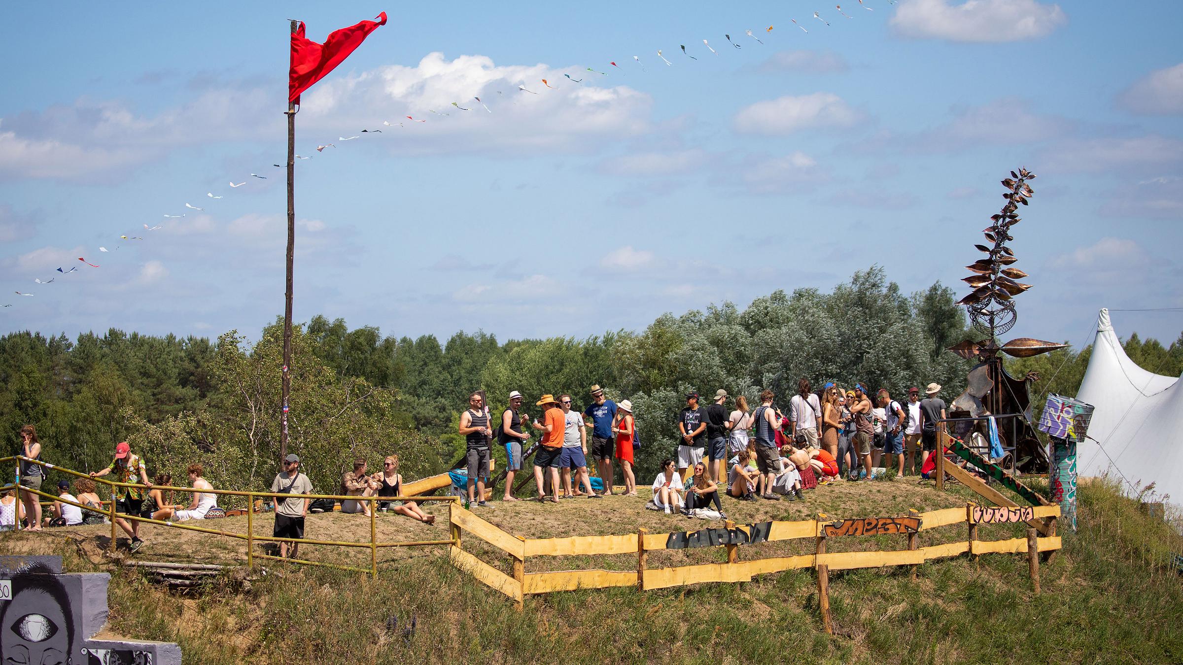 Festivalbesucher stehen auf einem alten Flugzeughangar für ein Erinnerungsfoto zusammen.