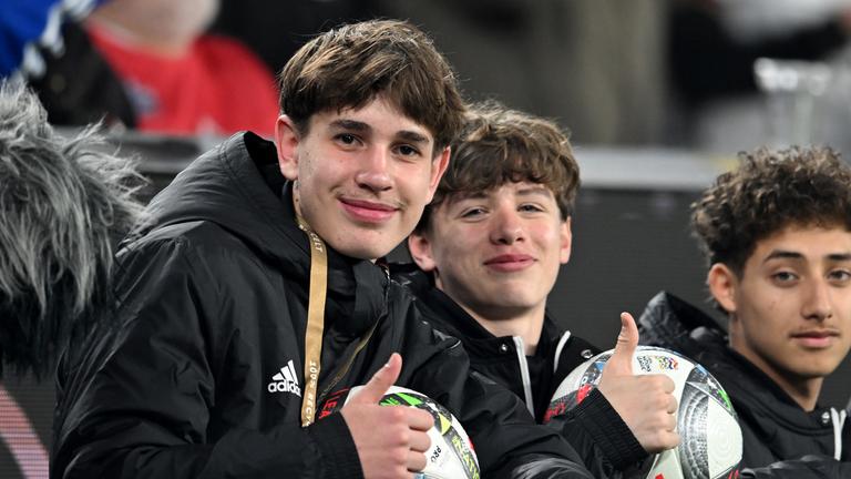 Balljunge Noel Urbaniack (l) und weitere Balljungen sitzen hinter der Bande.