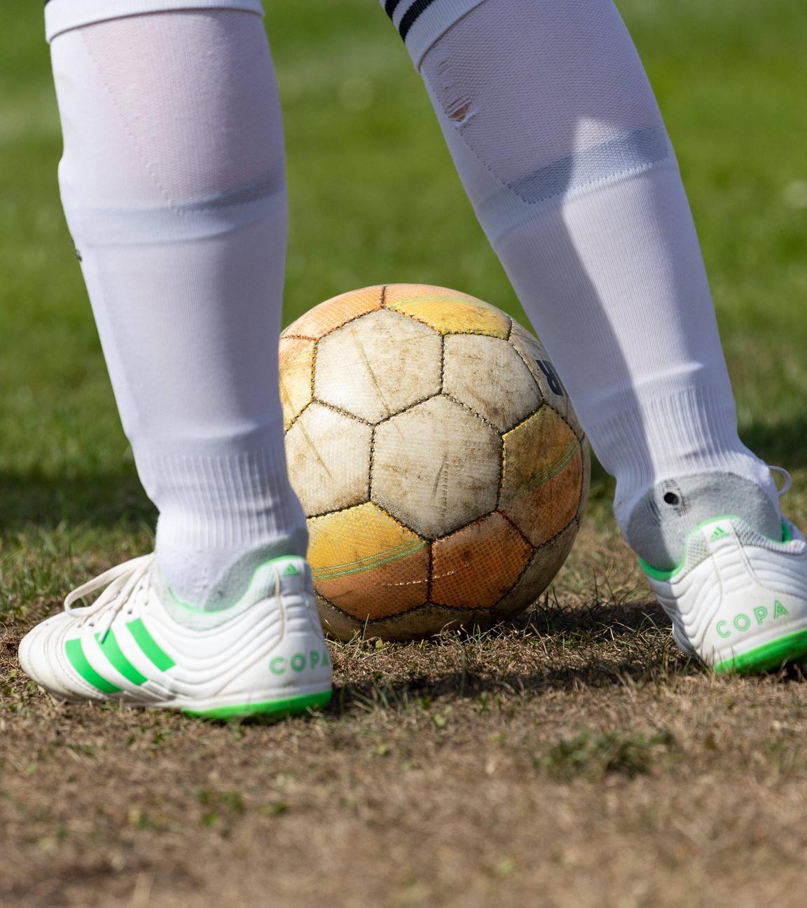 Ein Fussball liegt auf ausgetrocknetem Rasen. 
