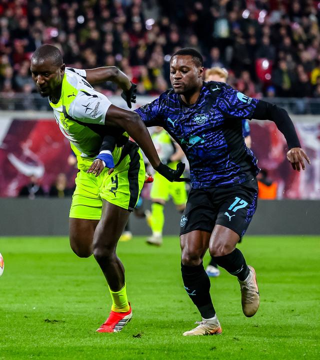 Serhou Guirassy (Borussia Dortmund) und Ridle Baku (RB Leipzig) kämpfen. 