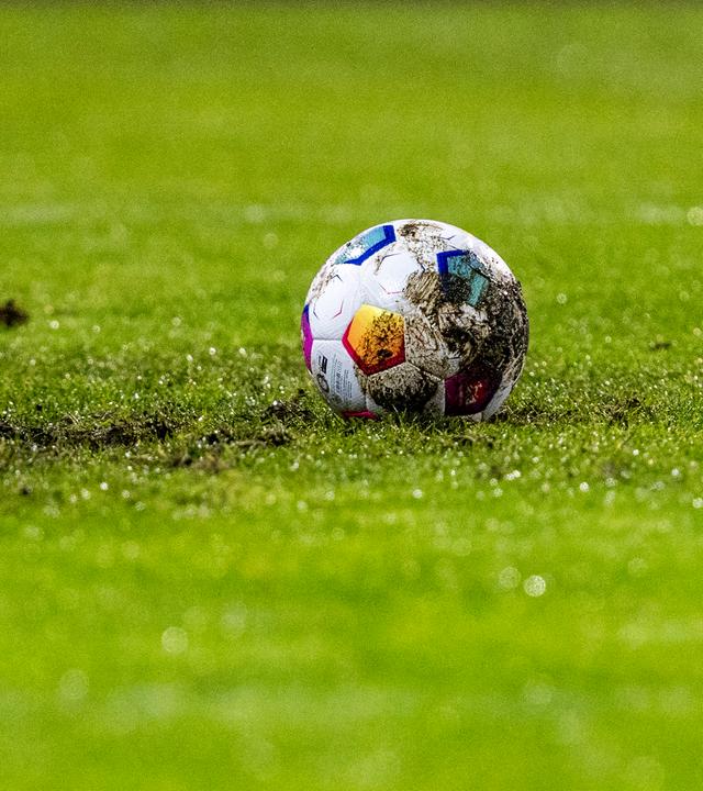 Ein Fußball liegt auf einem matschigen Fußballfeld