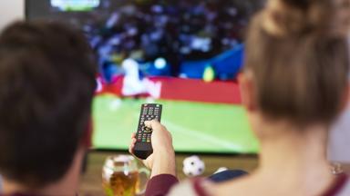 Mann und Frau vor dem Fernseher gucken Fußball zu Hause.