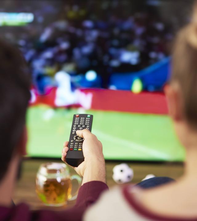 Mann und Frau vor dem Fernseher gucken Fußball zu Hause.