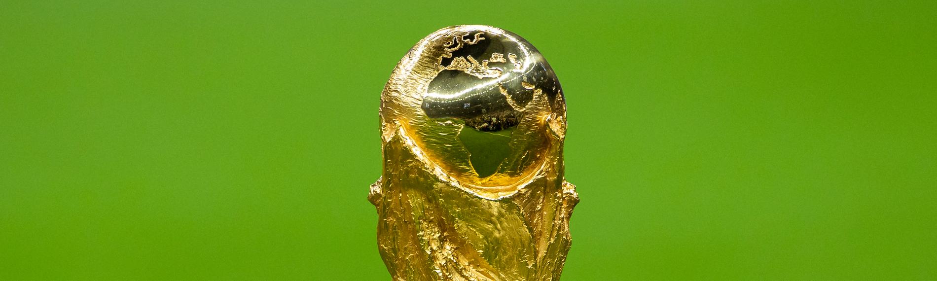 Die WM-Trophäe vor einem grünen Rasen.