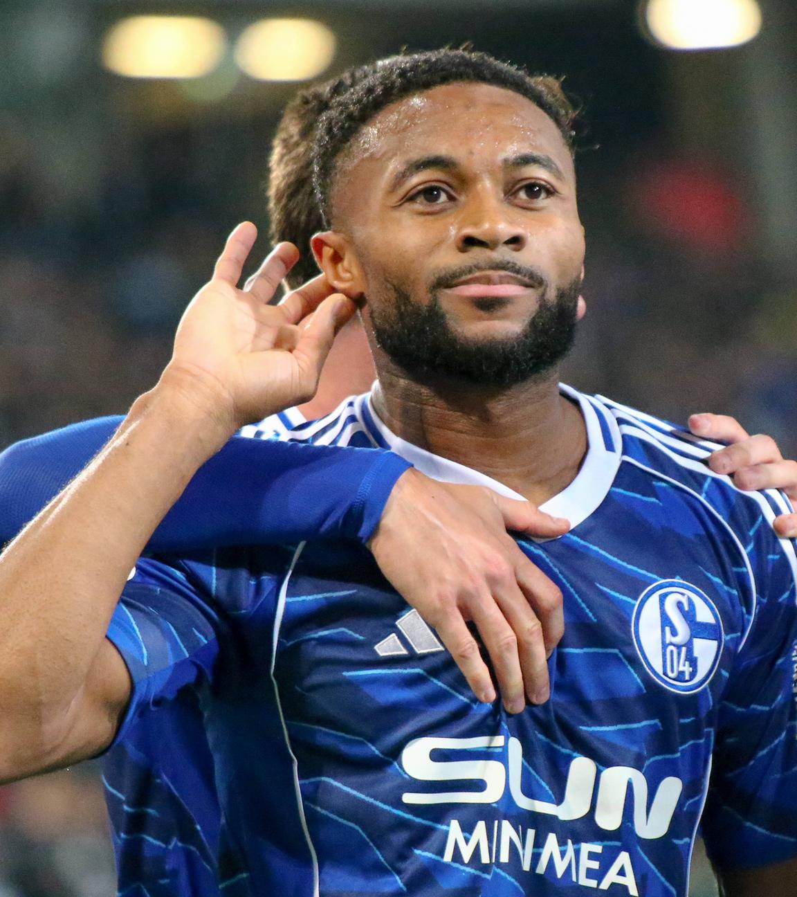 Fußballer Moussa Sylla von FC Schalke 04 hält seine Hand an sein Ohr, um den Jubel der Fans vermeintlich besser hören zu können.