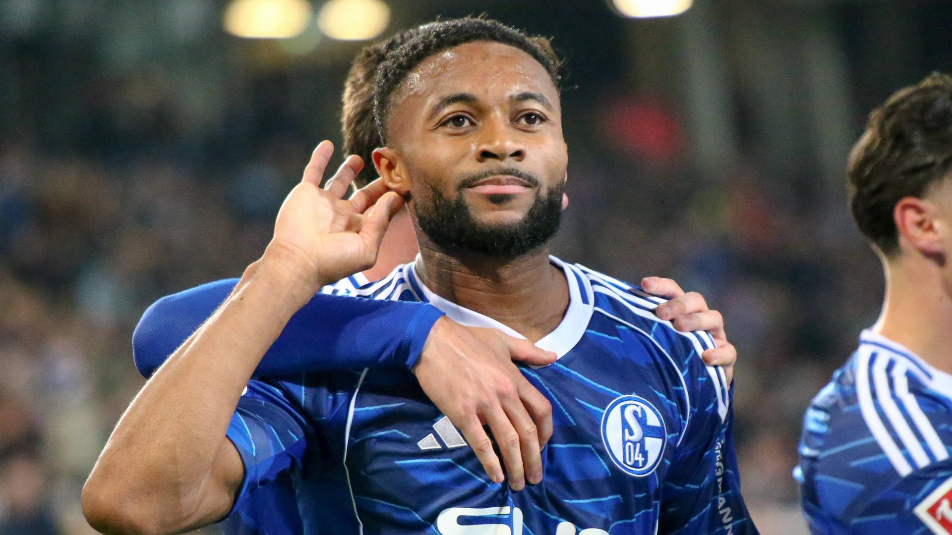 Fußballer Moussa Sylla von FC Schalke 04 hält seine Hand an sein Ohr, um den Jubel der Fans vermeintlich besser hören zu können.