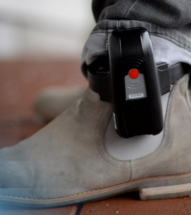 Ein Schuh mit einer darüber angebrachten elektronischen Fußfessel.