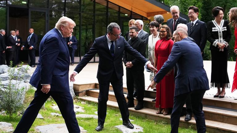 US-Präsident Donald Trump wird dabei unterstützt, sich der Treppe für ein Gruppenfoto der Staats- und Regierungschefs beim G7-Gipfel am Dienstag, dem 16. 6. 2026, in Évian-les-Bains, Frankreich, zu nähern. 
