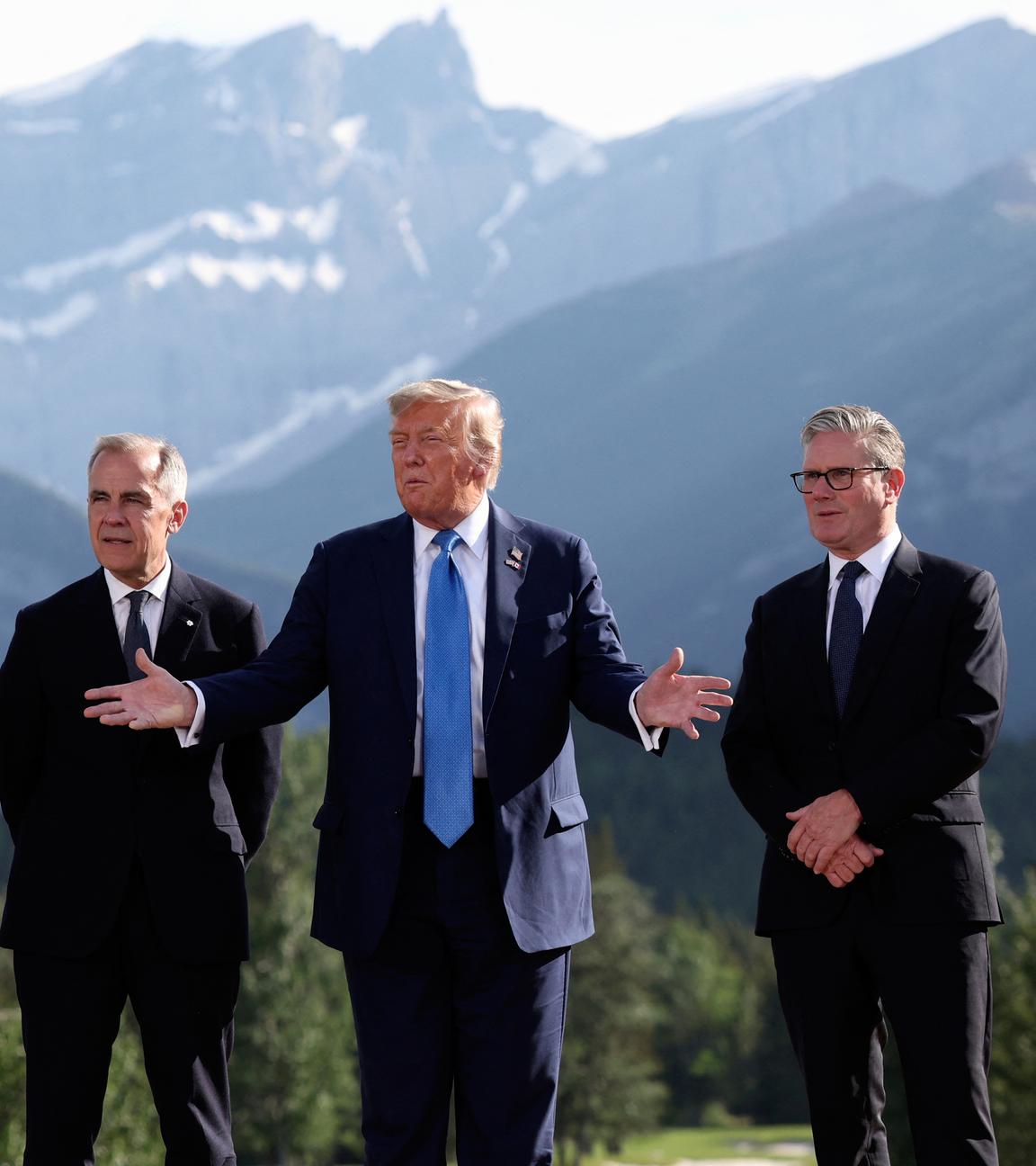 Macro, Carney, Trump, Starmer und Merz stehen nebeneinander, Trump spricht und gestikuliert, im Hintergrund ein Bergpanorama