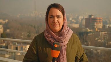 ZDF-Korrespondetin Phoebe Gaa steht mit einem Mikrofon vor Gebäuden in der iranischen Hauptstadt Teheran.