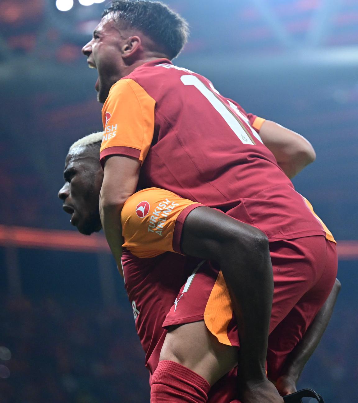 Galatasarays Torschütze Victor Osimhen nimmt einem Mitspieler huckepack und jubelt.