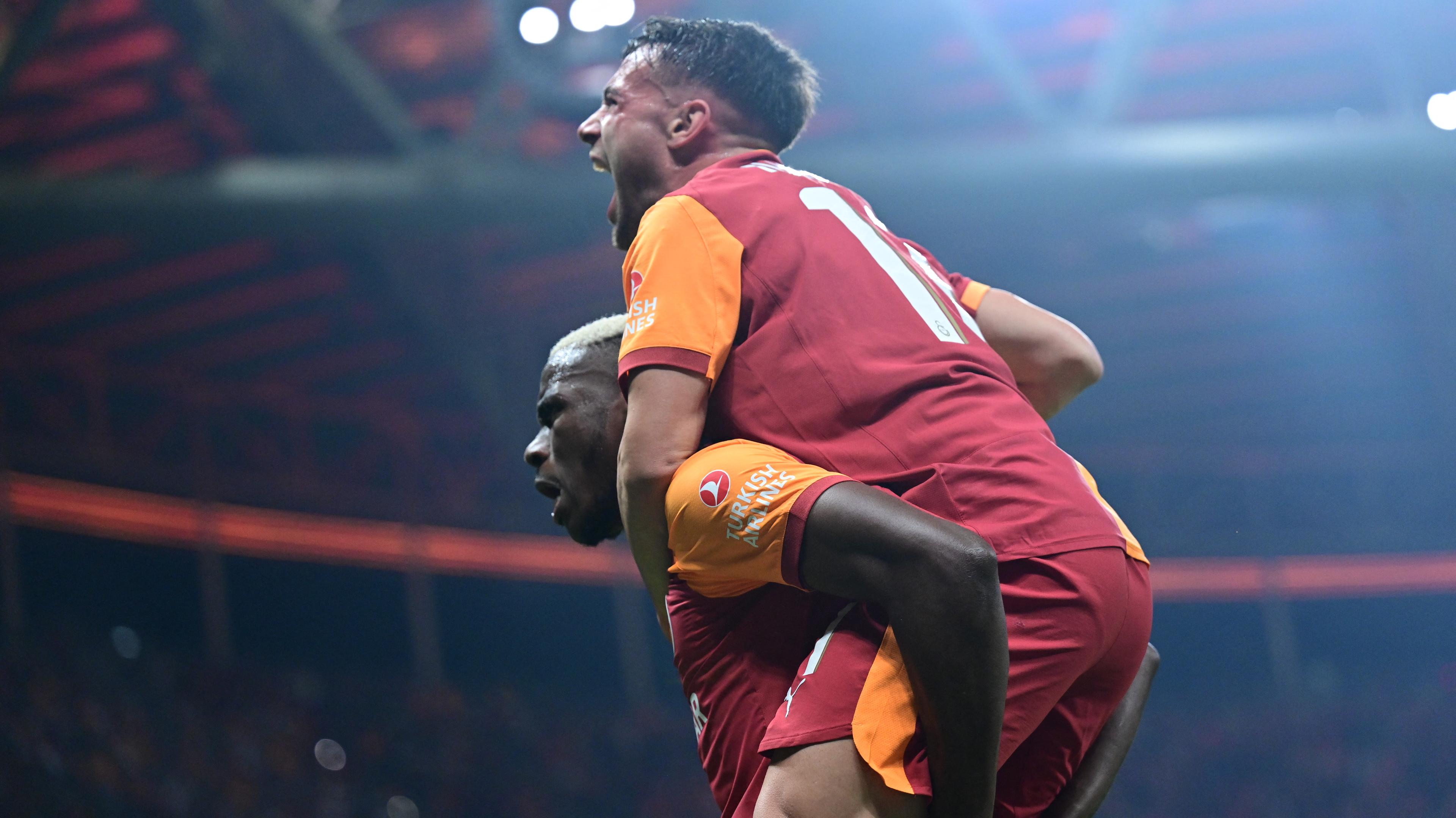 Galatasarays Torschütze Victor Osimhen nimmt einem Mitspieler huckepack und jubelt.