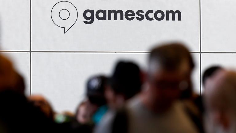 Besucher stehen Schlange vor dem Logo der Gamescom.