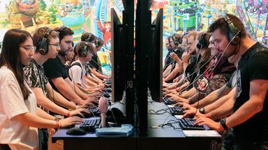 Besucher bei der Gamescom an Computern