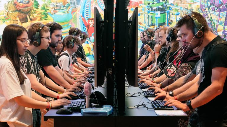 Besucher bei der Gamescom an Computern