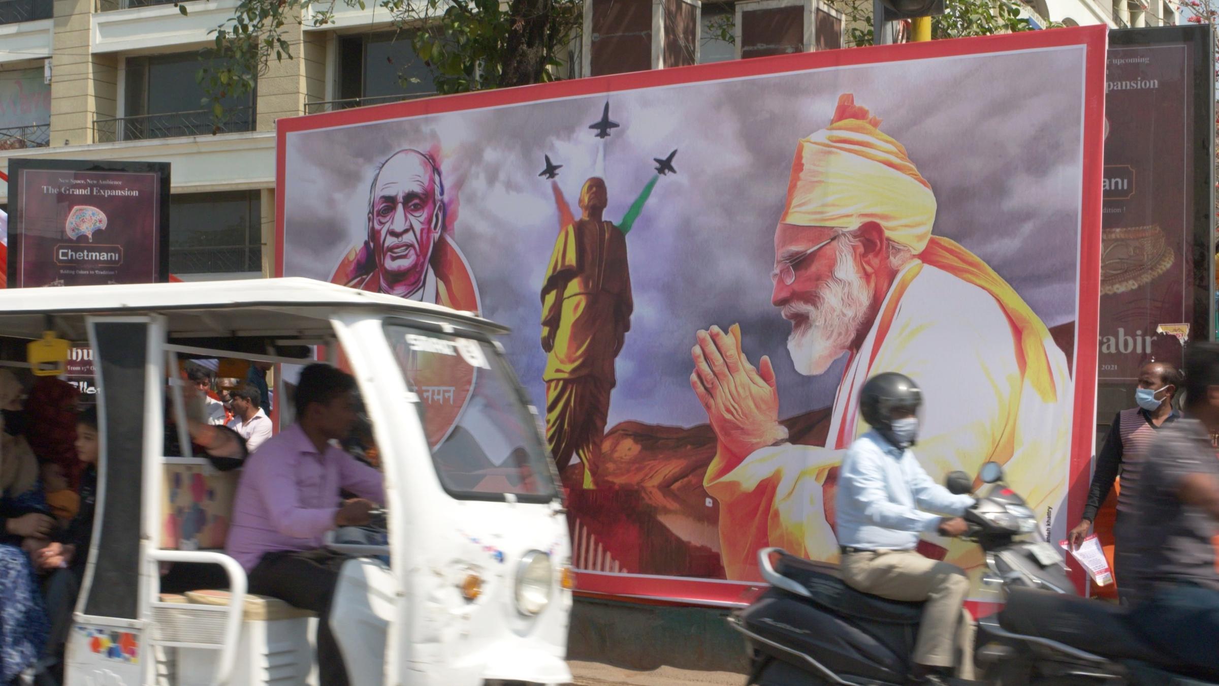  Straßenszene mit Mopeds, großes Wahlplakat der Regierungspartei BJP, auf dem Premierminister Narendra Modi zu sehen ist.