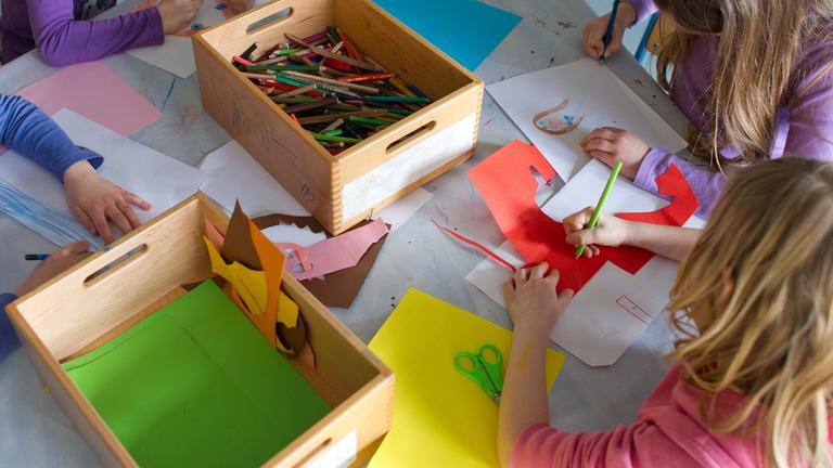 Symbolbild: Grundschülerinnen sind in einem Kinderhort mit Bastelarbeiten beschäftigt.