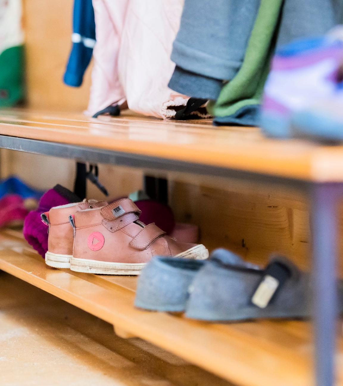 Kinderschuhe stehen auf einem Schuhregal in einer Kita.