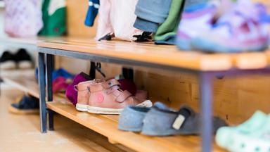 Kinderschuhe stehen auf einem Schuhregal in einer Kita.