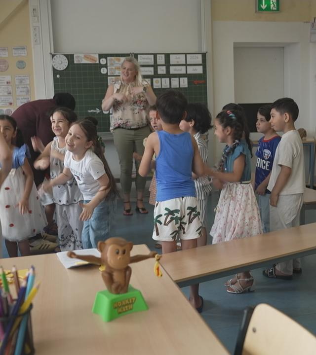 Erzieher und Kindern stehen klatschend im Kreis