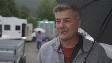 Das Bild zeigt Schauspieler Marcus Mittermeier mit einem Regenschirm am Set.