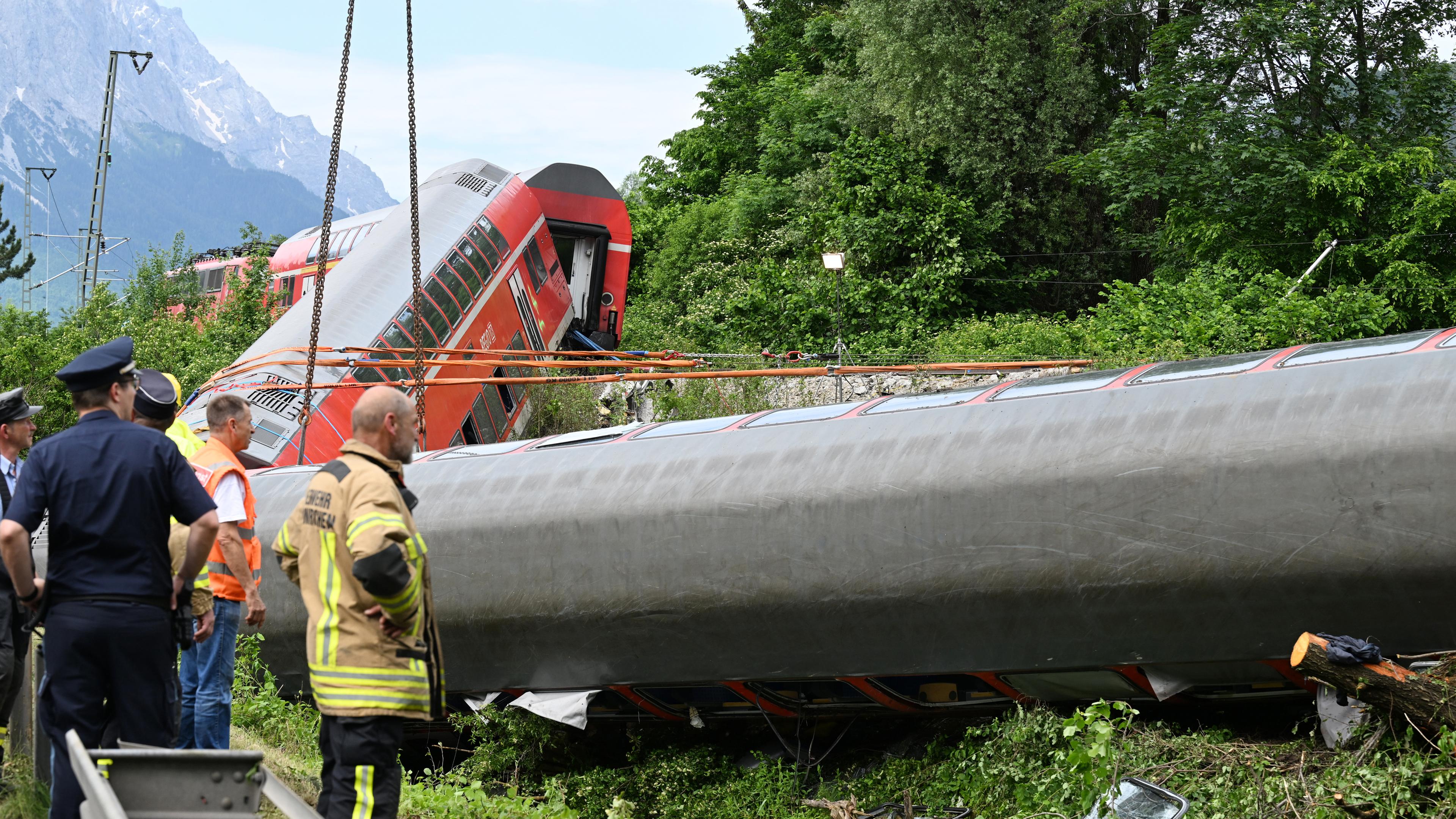 Einsatzkräfte betrachten einen zerstörten Zug.