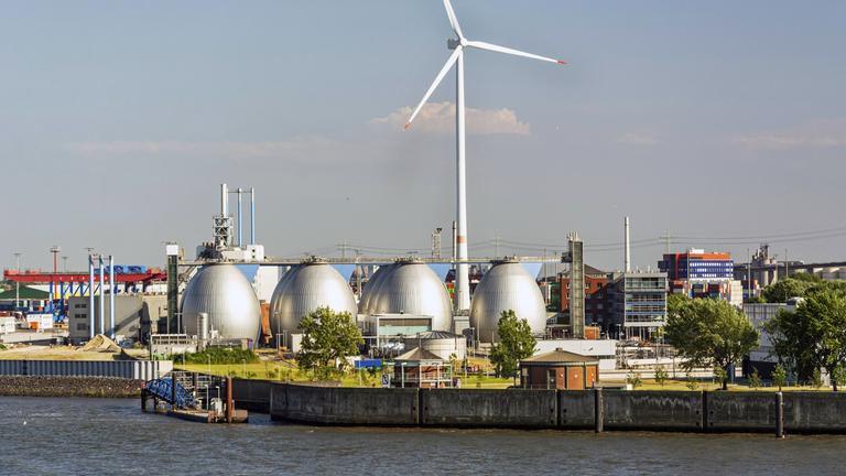 Gasspeicher und große Windkraftanlage im Hafengebiet von Hamburg, Deutschland.