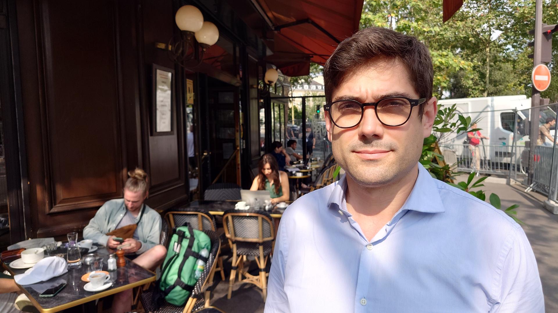 Romain Vidal steht vor seinem Bistro in Paris. Im Hintergrund sieht man die Absperrgitter der Sperrzone.