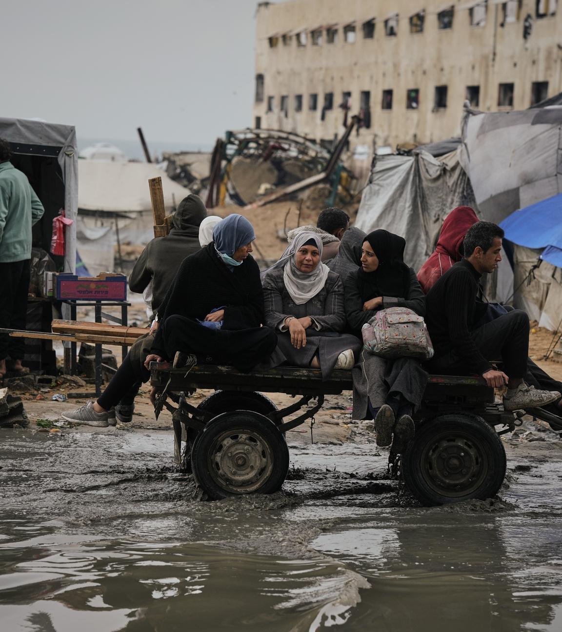 Palästinenser fahren in einem Karren, der von einem Fahrzeug gezogen wird, durch eine überflutete Straße nach einem Unwetter in Gaza Stadt