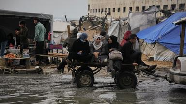 Palästinenser fahren in einem Karren, der von einem Fahrzeug gezogen wird, durch eine überflutete Straße nach einem Unwetter in Gaza Stadt