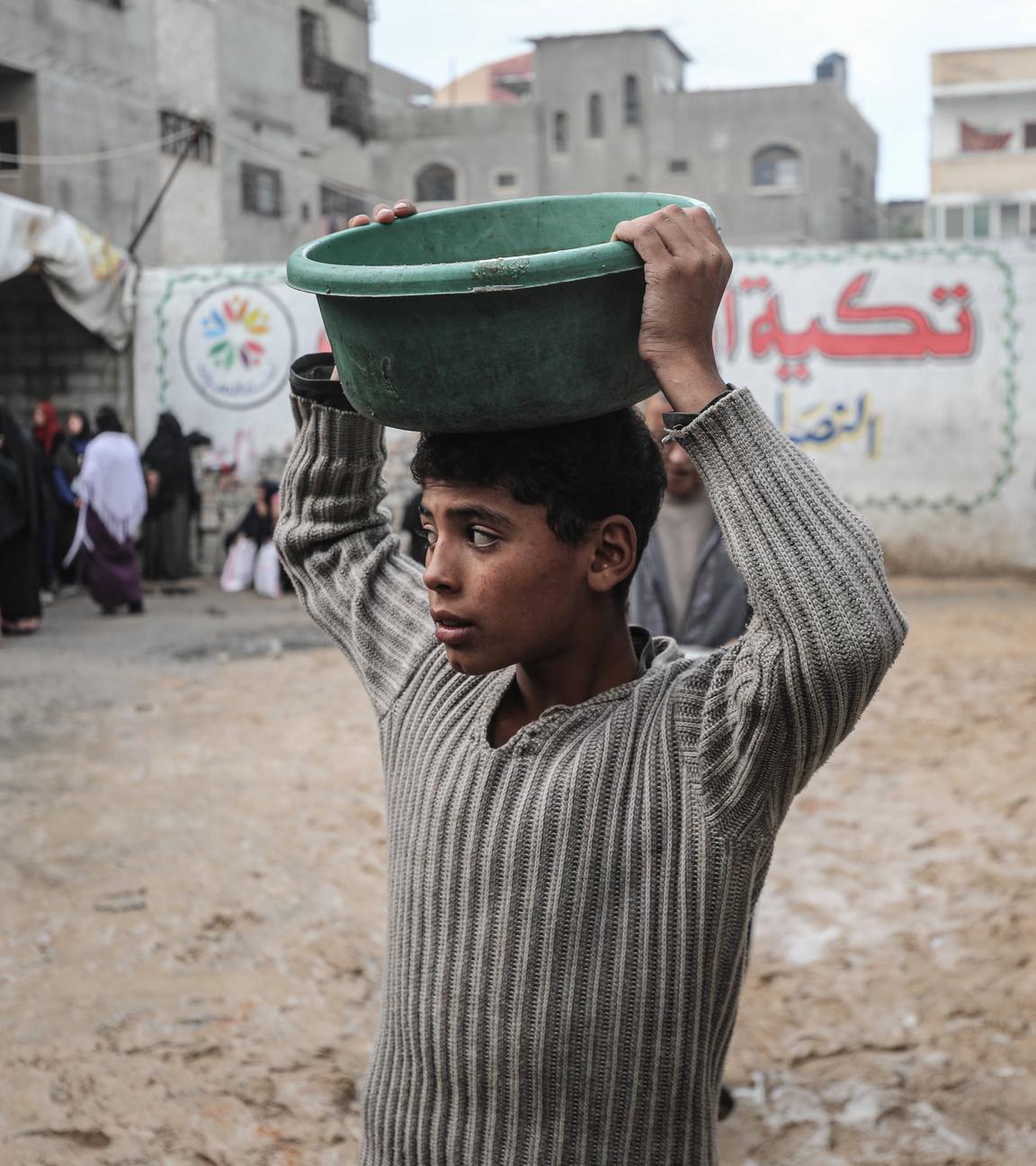 Vertriebene Palästinenser erhalten Mahlzeiten, die von einer Wohltätigkeitsorganisation im Lager Nuseirat verteilt werden, während die Nahrungsmittelkrise aufgrund von Beschränkungen für humanitäre Hilfslieferungen in Deir al-Balah, Gaza, am 13.12.2025 weiter anhält.