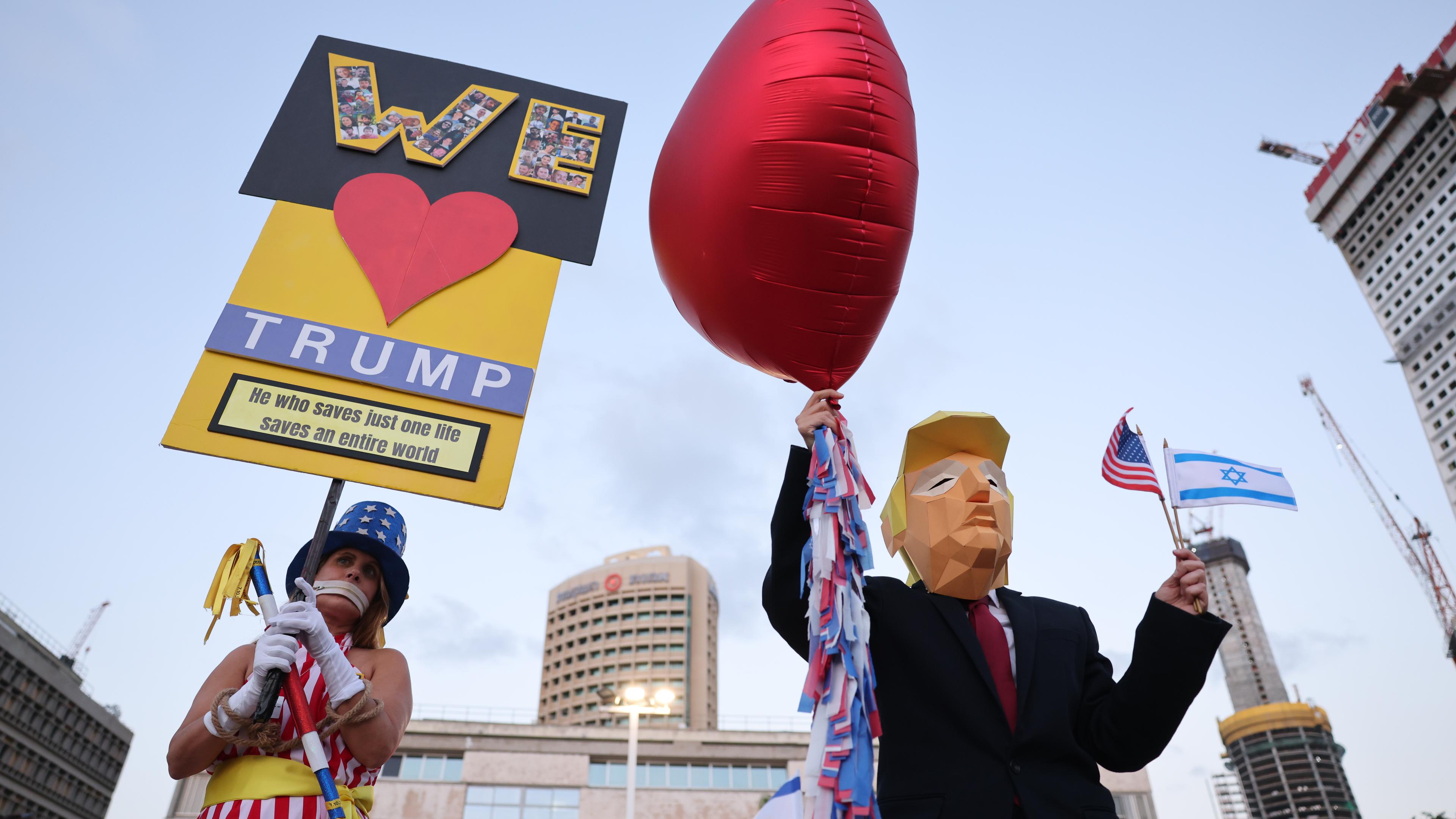 Eine Pappfigur von Trump mit Herz-Luftballon, daneben eine Demonstrantin mit "We Love Trump"-Schild.