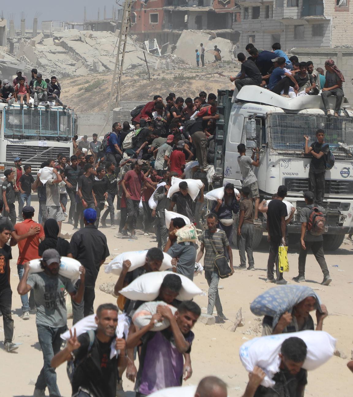 Menschen bewegen sich am 27.07.2025 auf der al-Rashid-Straße in West-Jabalia zu Hilfstrucks, die über den israelisch kontrollierten Übergang Zikim in den Norden Gazas gelangten.