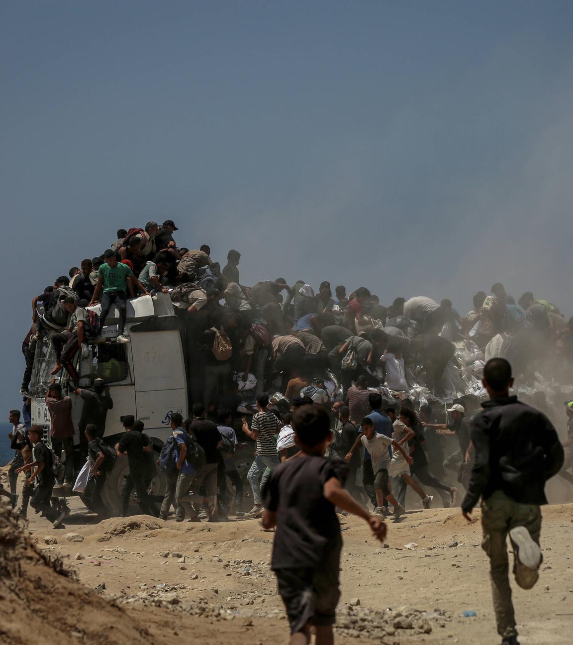 Palästinenser laufen kilometerweit, nachdem sie Mehlhilfen erhalten haben, die von Lastwagen verteilt wurden, die in das Gebiet Zikim, einen Kibbuz im Süden Israels, gefahren sind, während die israelischen Angriffe andauern und es zu schweren Nahrungsmittelengpässen kommt, in Gaza-Stadt, Gaza, am 27. Juli 2025.