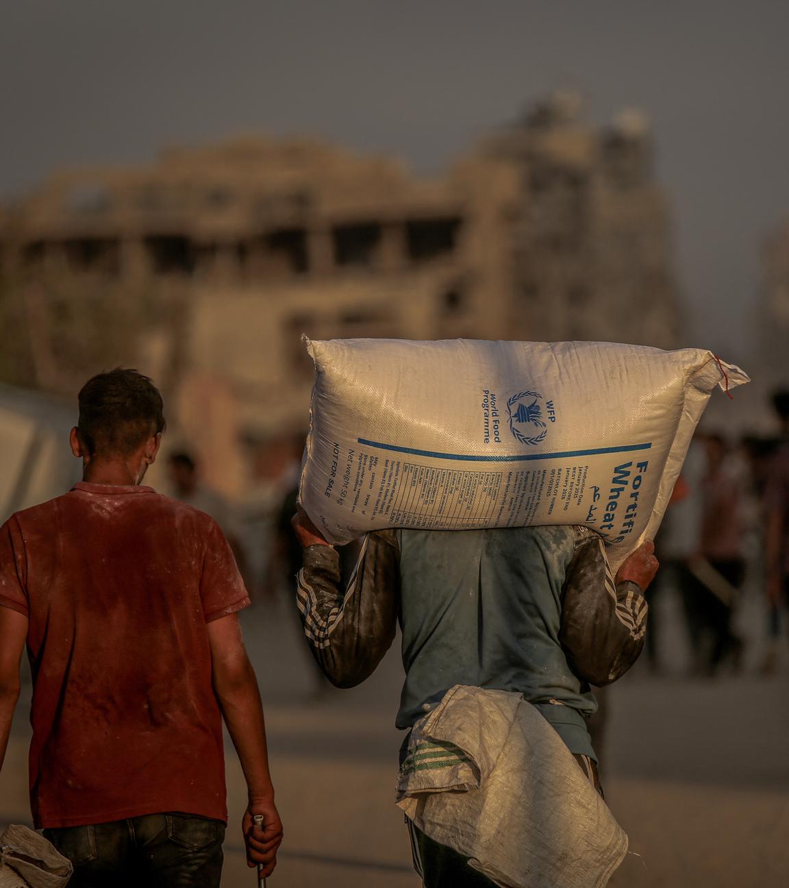 Ein Mann in Gaza trägt einen Sack Weizen auf seinen Schultern.