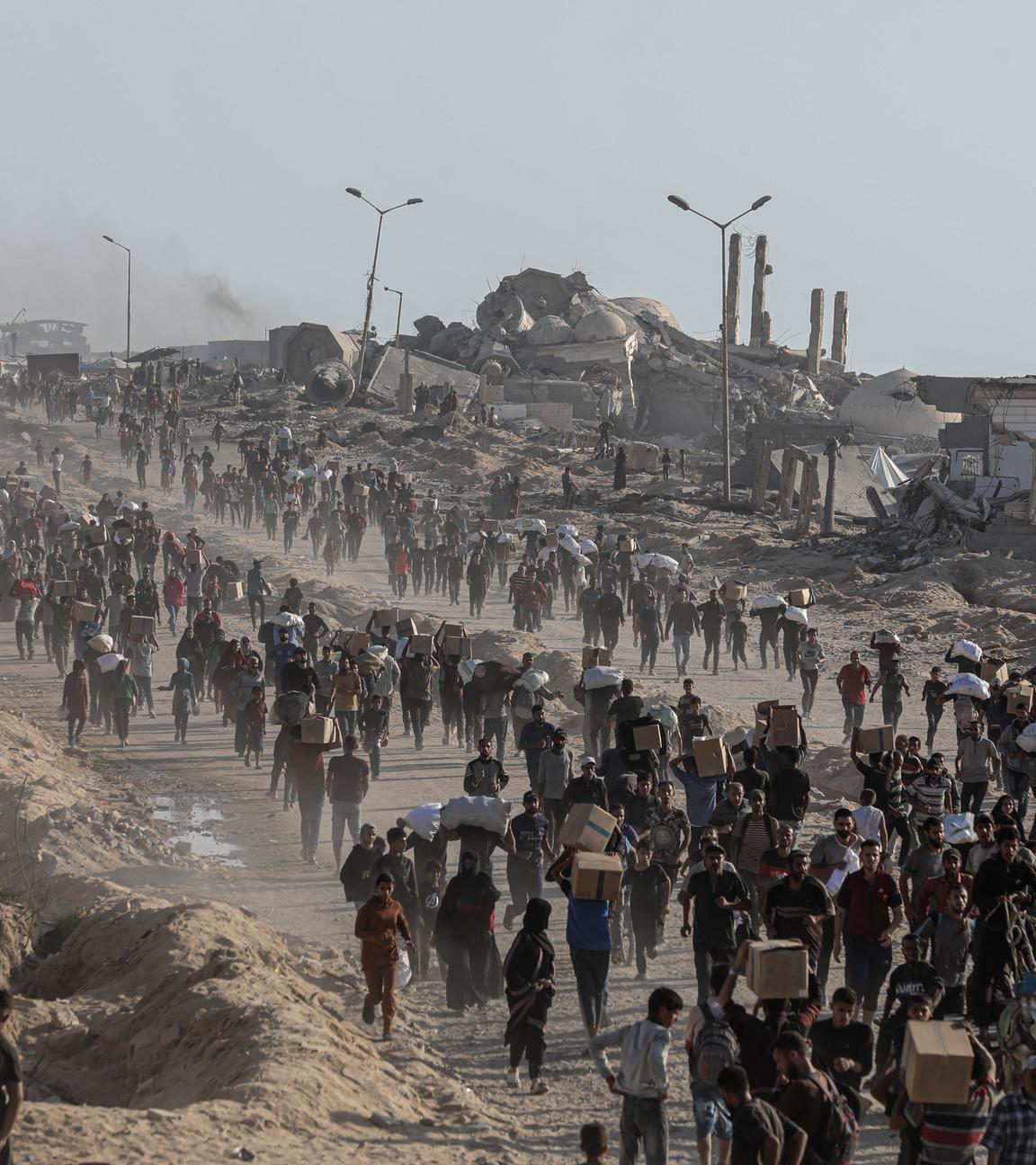 16.06.2025, Palästinensische Gebiete, Gaza-Stadt: Palästinenser tragen Lebensmittelpakete, die von der The Gaza Humanitarian Foundation (GHF) verteilt wurden.