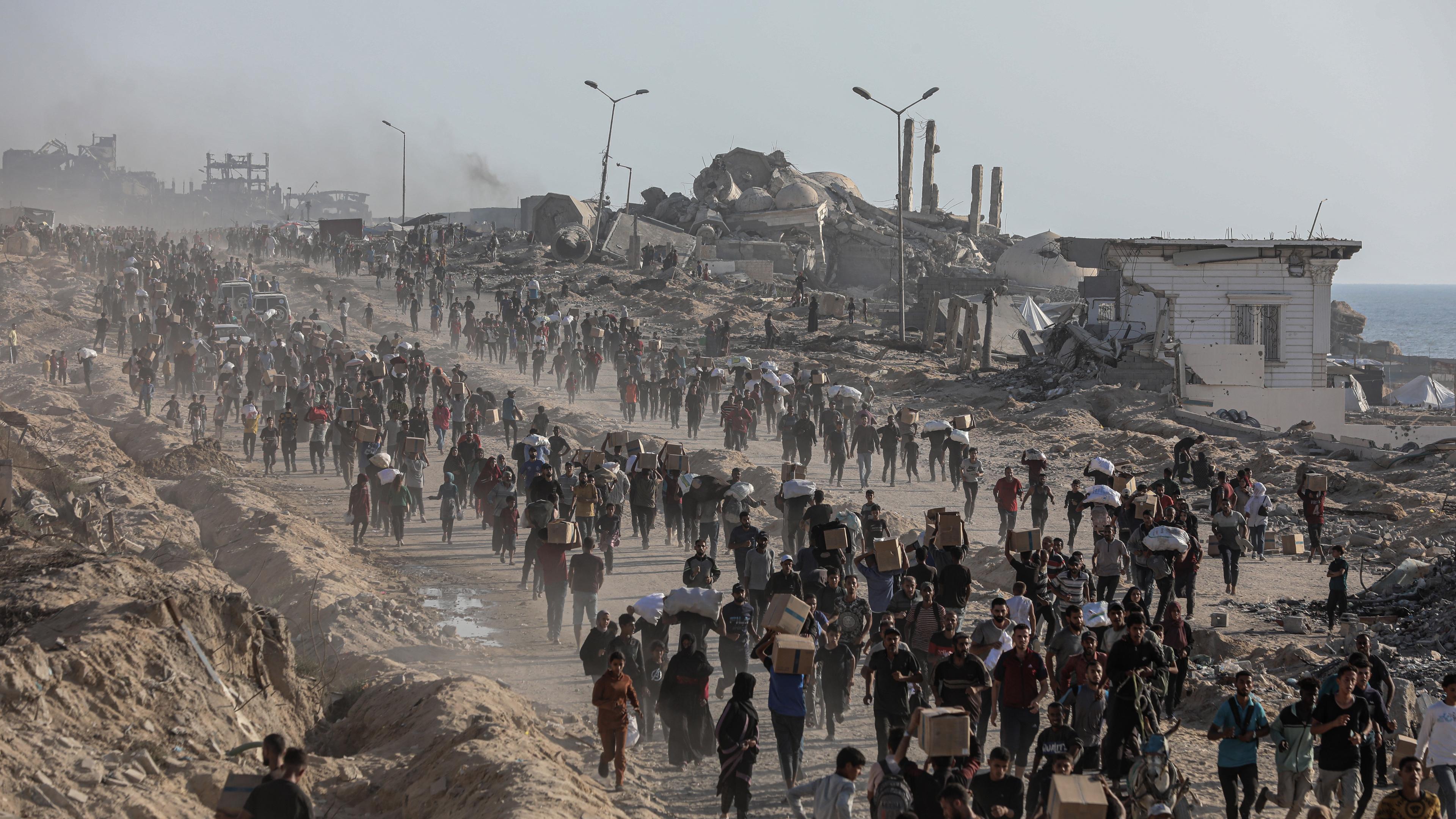 16.06.2025, Palästinensische Gebiete, Gaza-Stadt: Palästinenser tragen Lebensmittelpakete, die von der The Gaza Humanitarian Foundation (GHF) verteilt wurden.
