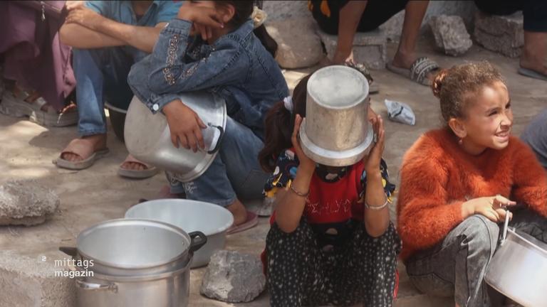 Kinder warten mit Töpfen auf Essen