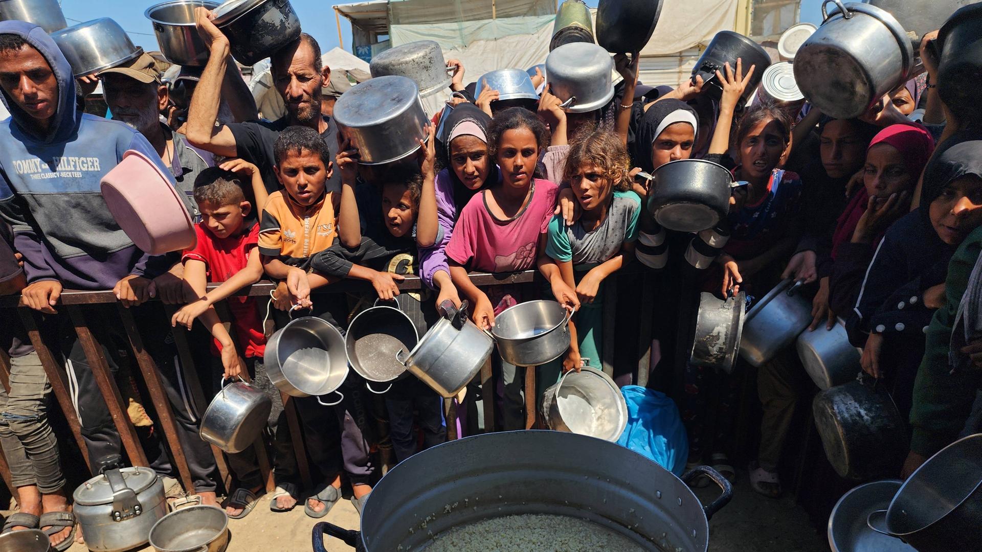 Viele Kinder warten dicht gedrängt mit Töpfen in den Händen auf die Essensausgabe.