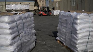 Gestapelte und in weiße Verpackung gehüllte Hilfsgüter auf Paletten