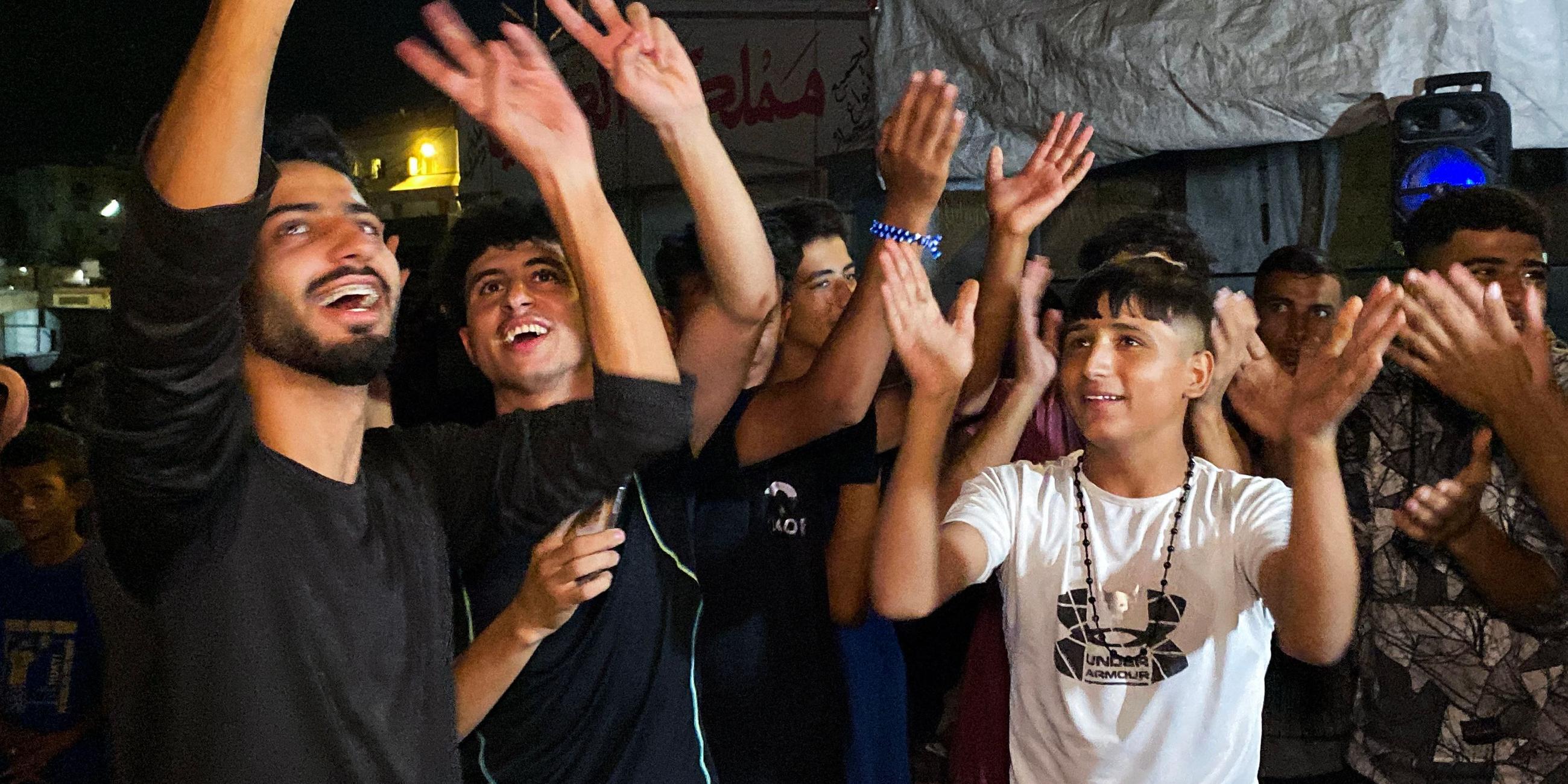 Khan Yunes, Palästinensiche Gebiete: Mehrere Menschen feiern auf einer Straße nach der Verkündung, dass Israel und die Hamas sich auf die Umsetzung der ersten Phase des Friedensplans geeinigt haben.