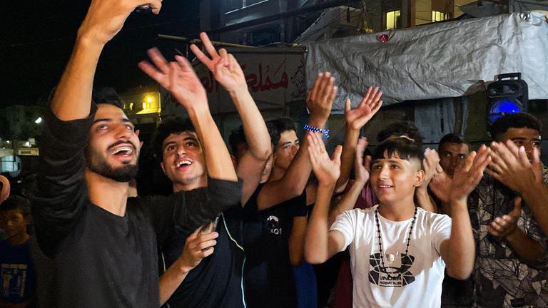 Khan Yunes, Palästinensiche Gebiete: Mehrere Menschen feiern auf einer Straße nach der Verkündung, dass Israel und die Hamas sich auf die Umsetzung der ersten Phase des Friedensplans geeinigt haben.